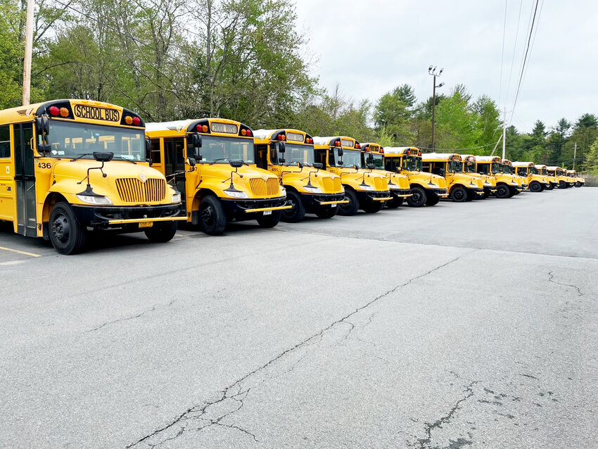 A row of busses in a parking lot.