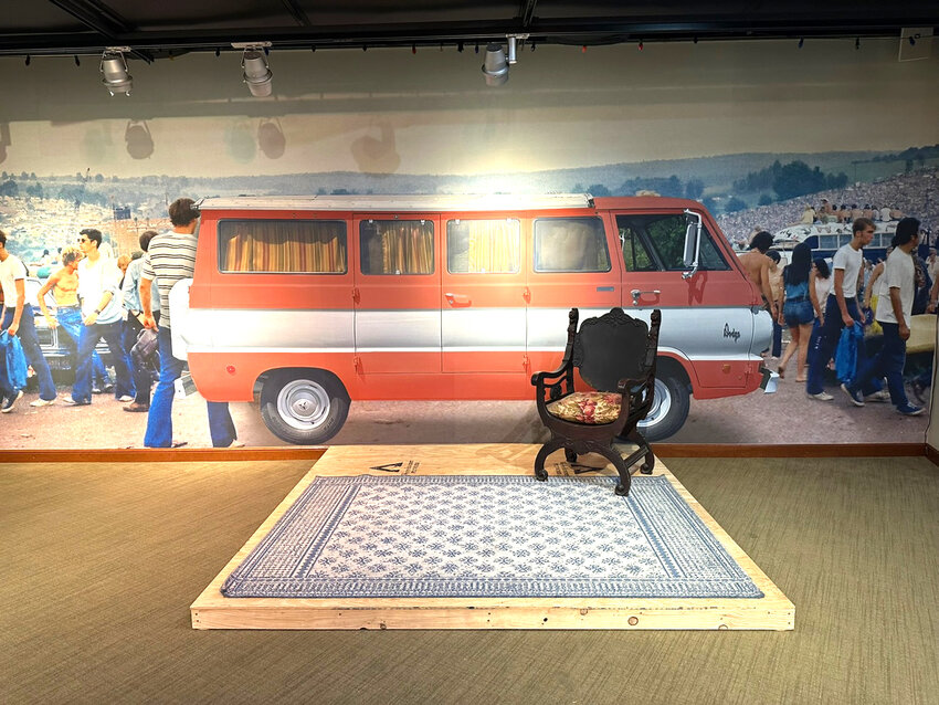 A camper van used as a vending area – the display in front of it is in progress but will feature the chair in the photo which is on loan from original Woodstock vendor Kenneth Bray. The photo in the background of that mural is by Tom Shea, BW Collection, gift of Tom Shea.