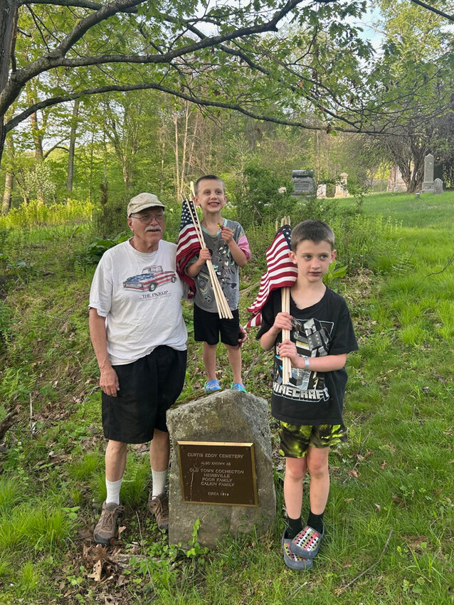 Keith Krauss, grandfather and veteran, was assisted by grandsons Kristopher and Alex Snedeker in placing American flags on the gravestones of veterans in honor of Memorial Day.