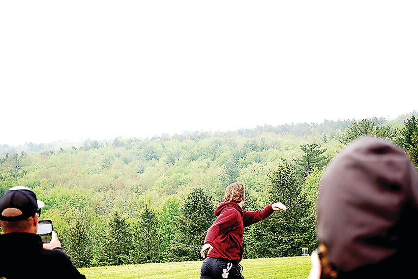 Carl McGuire, a 2017 Graduate of Liberty High School, is shown launching a disc towards the basket.
