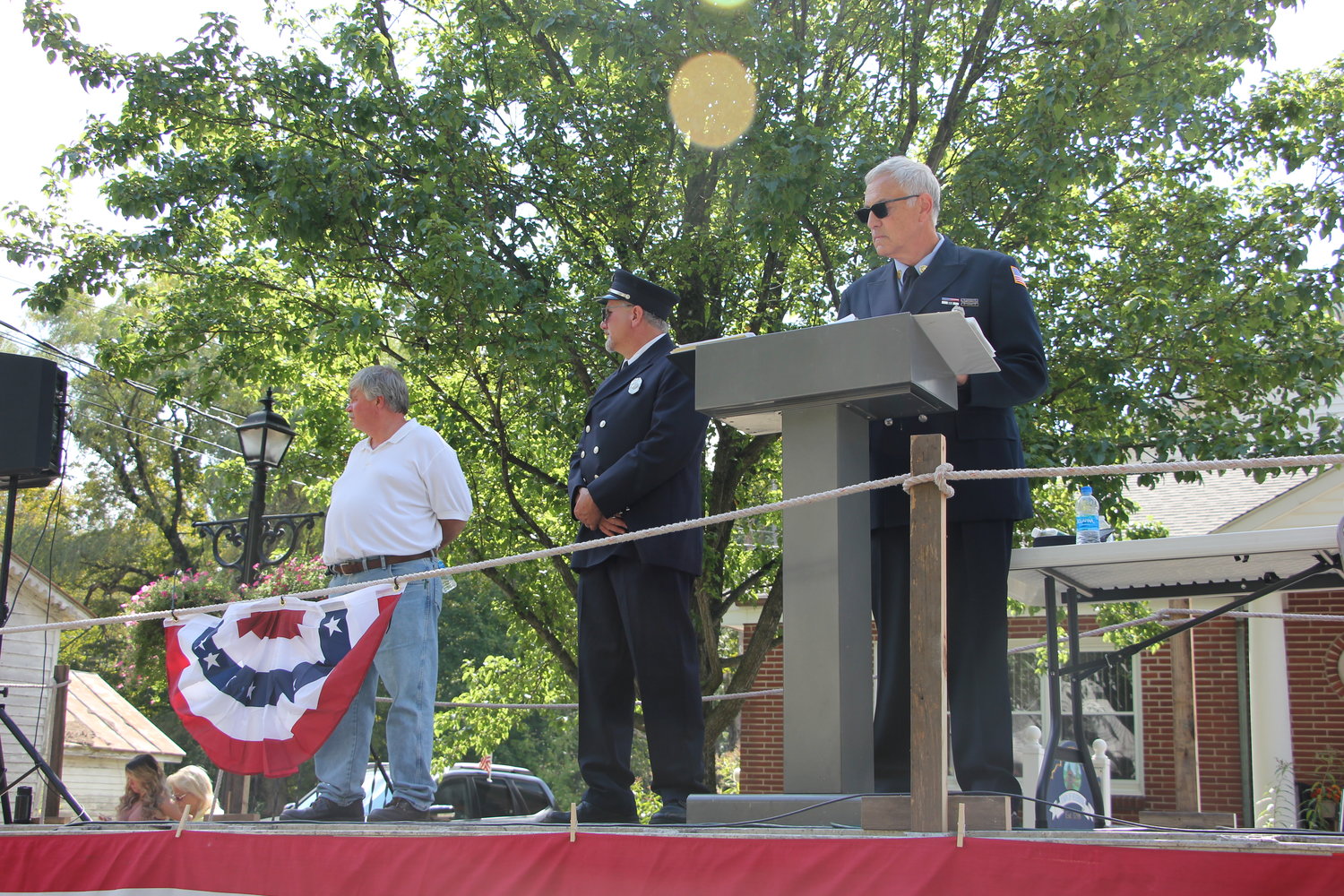 (l-r) County Clerk Russell Reeves, Town of Neversink Supervisor Chris Mathews and Master of Ceremonies, the Honorable Mark Meddaugh on the reviewing platform at the 92nd Annual Sullivan County Volunteer Firefighter’s Association parade in Grahamsville on Saturday.