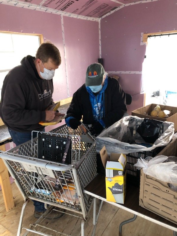 Kathy Kreiter (right) and Scott Mace preparing a shopping cart with enough food to feed at least one entire family in need.