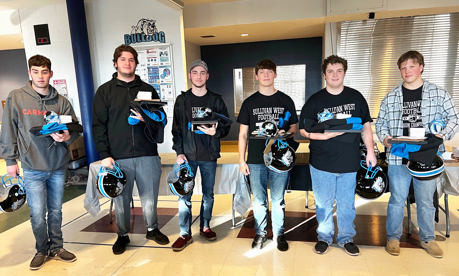 Sullivan West seniors hold the gifts they received including helmets, action shot framed photos, sweatshirts and watches that had a Division Champion logo on the face. Pictured from left to right: James McElroy, Chris Campanelli, Mike Roth, Justin Grund, Ryan Joyce Turner and Gavin Hauschild. Tarrell Spencer was unable to attend the banquet but his praises were also sung by the coaches.