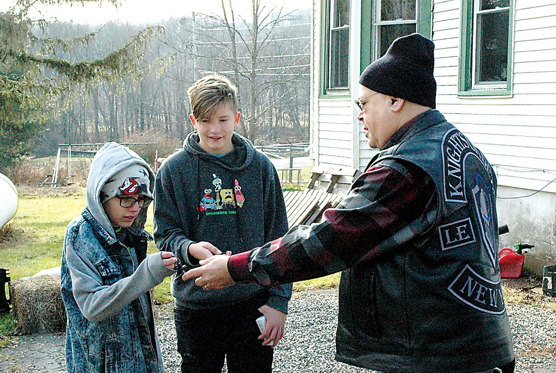 President of the Knights Order LEMC Sullivan County Chapter, Gabriel Espinosa, handing off the keys of the new bikes to recipients Austin and Cody.