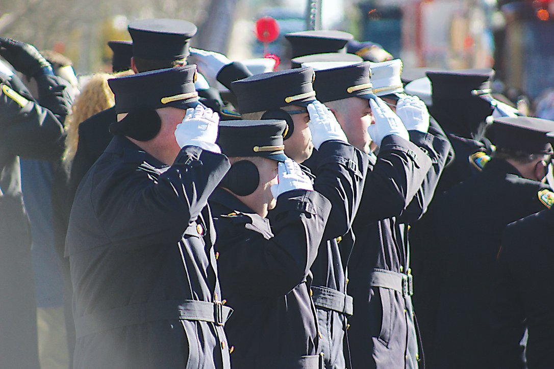Firefighters salute the funeral procession as it goes down Broadway, Monticello.