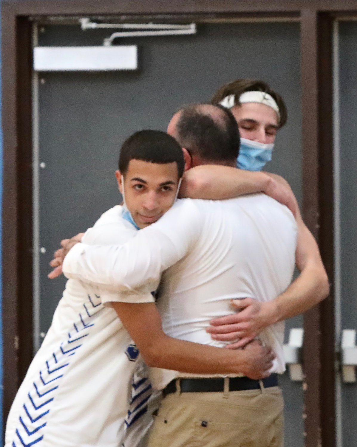 Coach Chris Russo gets an emotional hug from his son Joseph and star guard Pedro Rodriguez. Russo has such great rapport with his players who respect him immensely. Making it to sectionals was a season-long goal.