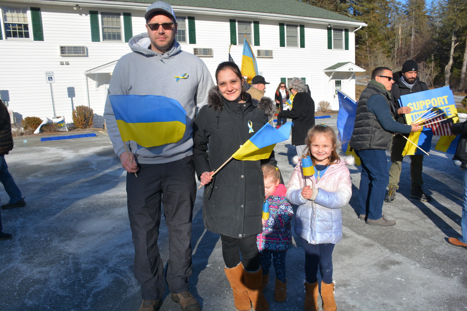 James and Natalie Steimle with daughters Julia (at right) and Michaela (hiding behind mom), proudly wave Ukrainian flags. Behind them to the right, handing out signs and flags, is rally organizer Frank Guzman and his husband Alexander Brito.