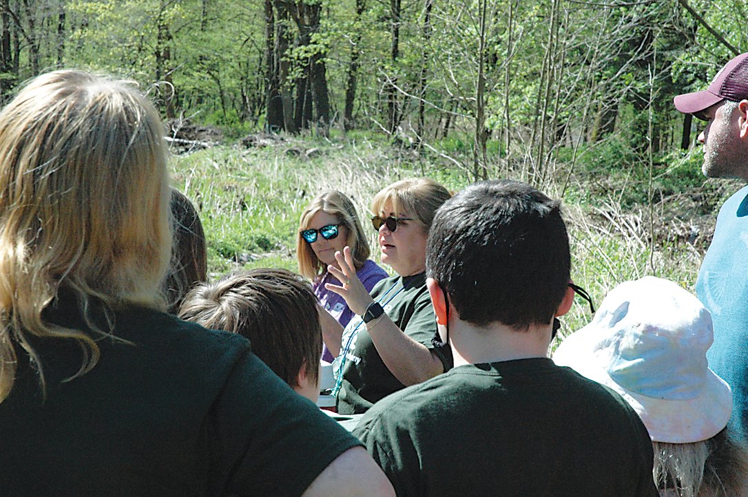 K-6 AIS Teacher at Sullivan West, Sue Mullally, center, reminds students of the importance of testing the water’s temperature and Ph balance before releasing the young trout.