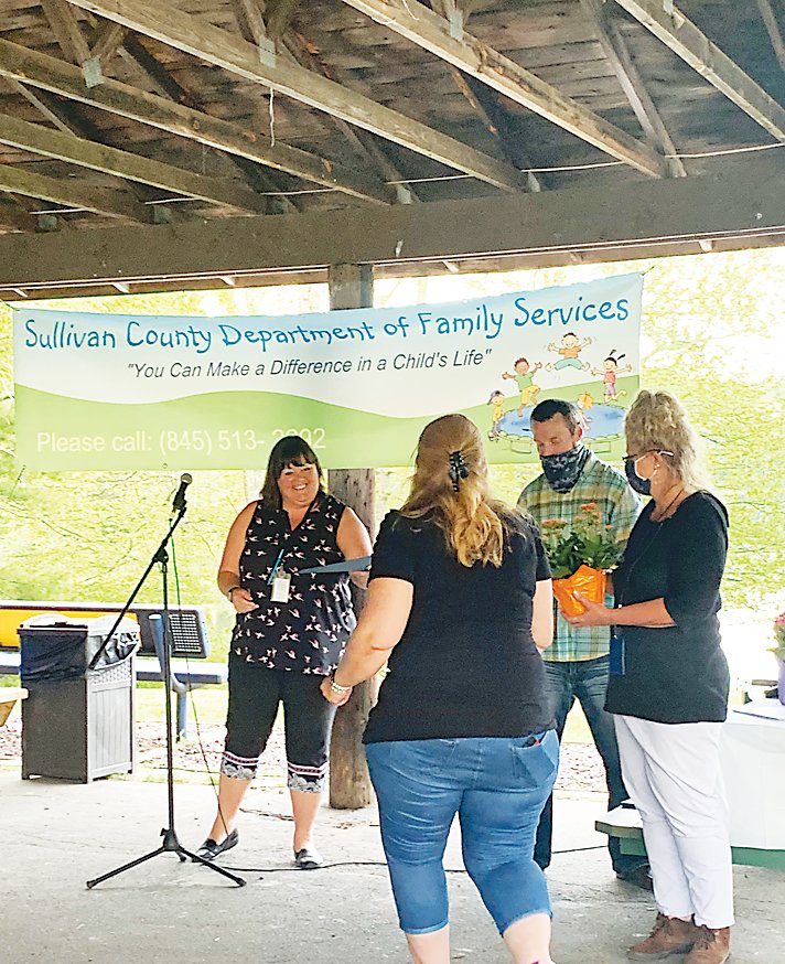 From left, Sullivan County Foster Care Case Supervisor Wendy Mason, and Senior Foster Care Caseworkers Michael Osepowicz and Kim Nash, present a local  foster parent with a certificate and gift at a recognition dinner held at Hanofee Park in Liberty last year.