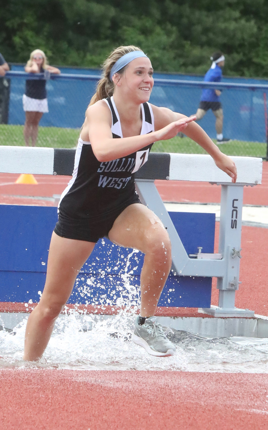 Sullivan West senior Grace Boyd smiles as she exits the water pit during her victory in the 2000 steeplechase. SW swept the event with the help of Ella Herbert and Brooke Nunnari for a 24-point SW addition to the winning ledger.