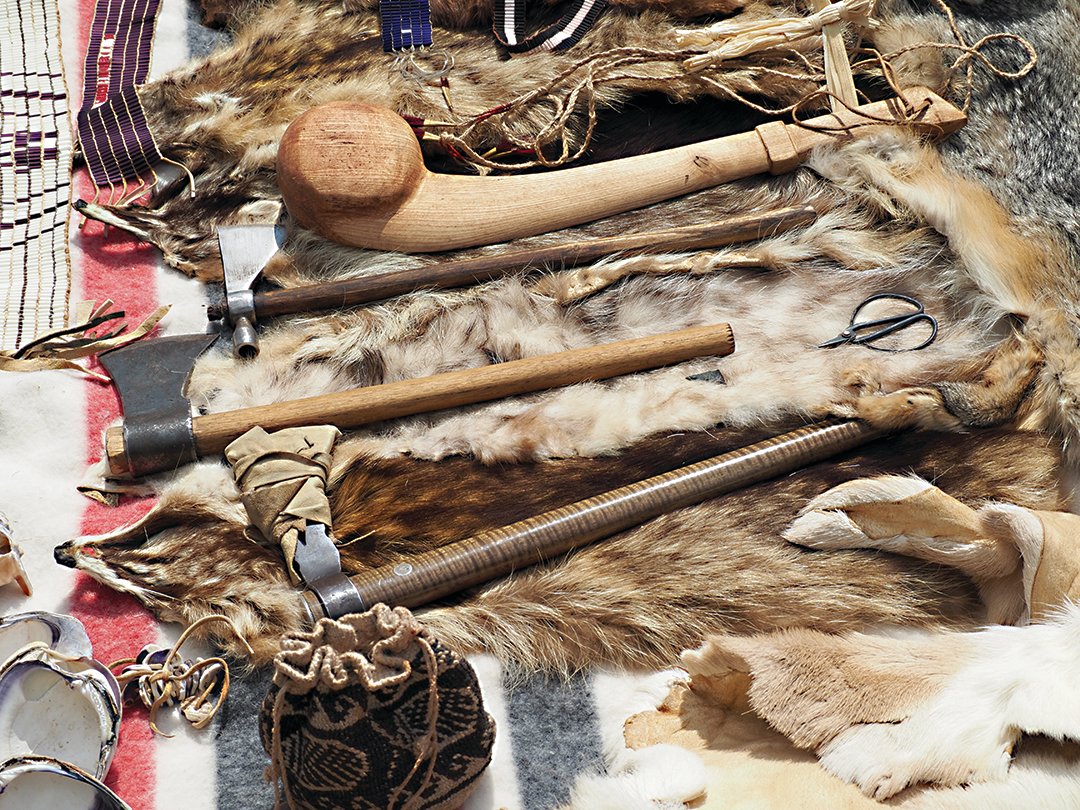 Among the items Rayvis showed the audience were wampum belts (upper left), a club made from the root of a tree, several “otomahuks” (from the Algonquian word “to knock down”), and shells to make beads from (lower left).