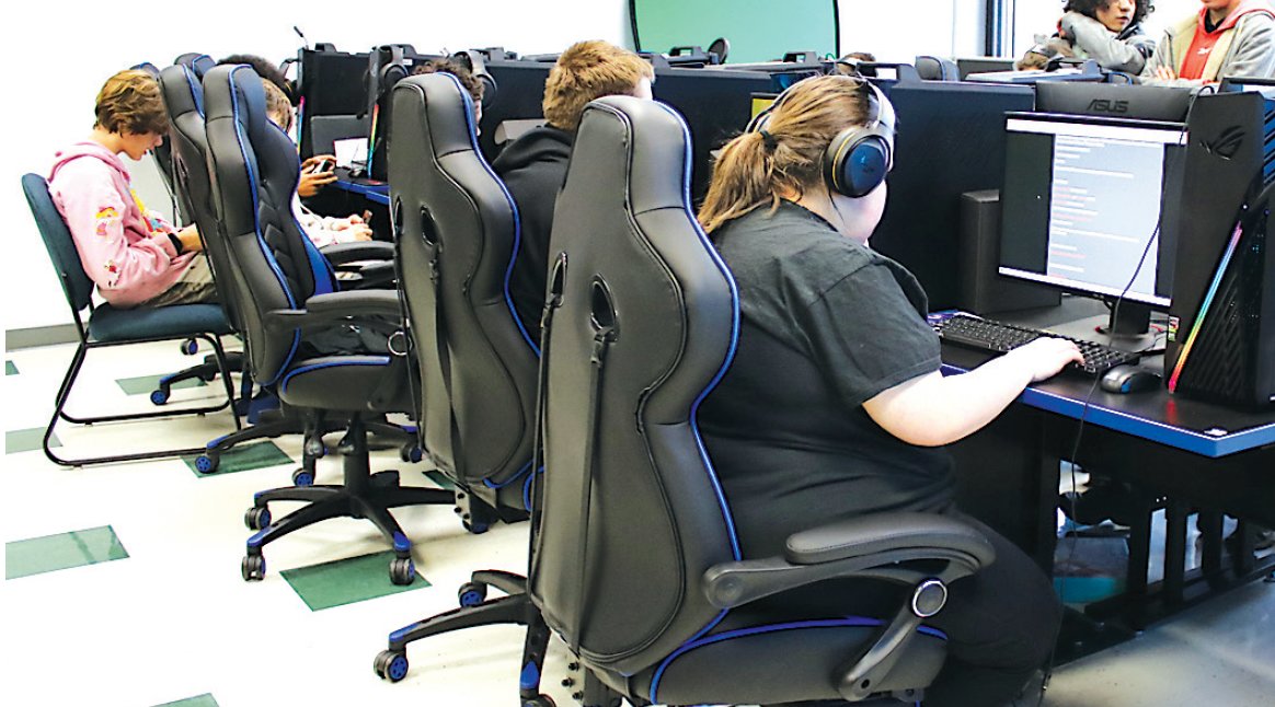 Every PC in the room is taken, so some students play alongside a friend or use a Switch.
