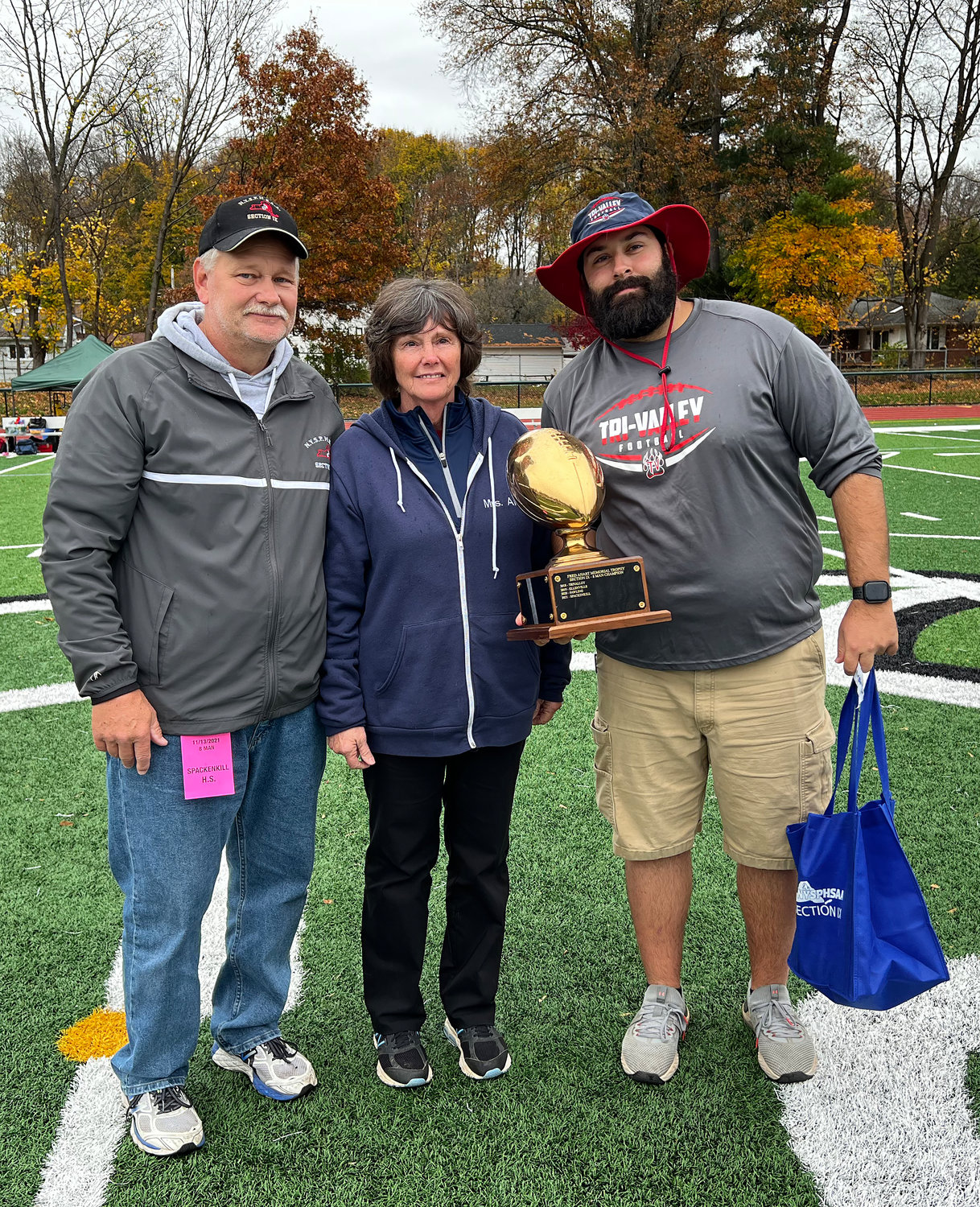 Tri-Valley head coach Kevin Crudele, right,  holds the Fred Ahart Eight-Man trophy presented by Becky Ahart and David Franskevicz.