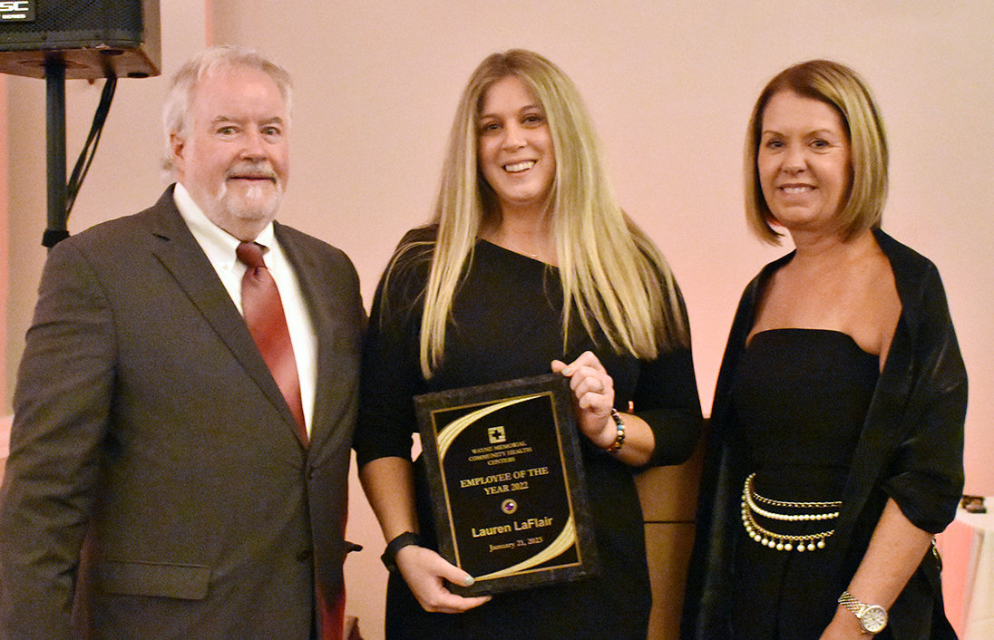 Lauren LaFlair (center) holding up her plaque for employee of the year with executive director Frederick Jackson (left) and incoming executive director Teresa Lacey (right).