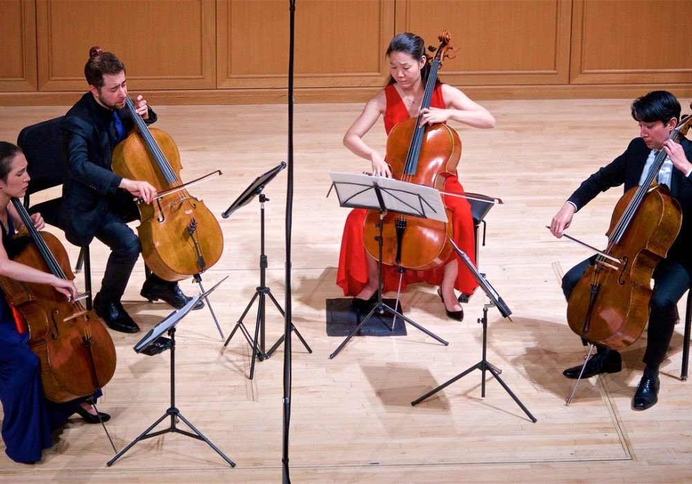 The Colorado Cello Quartet playing on stage.