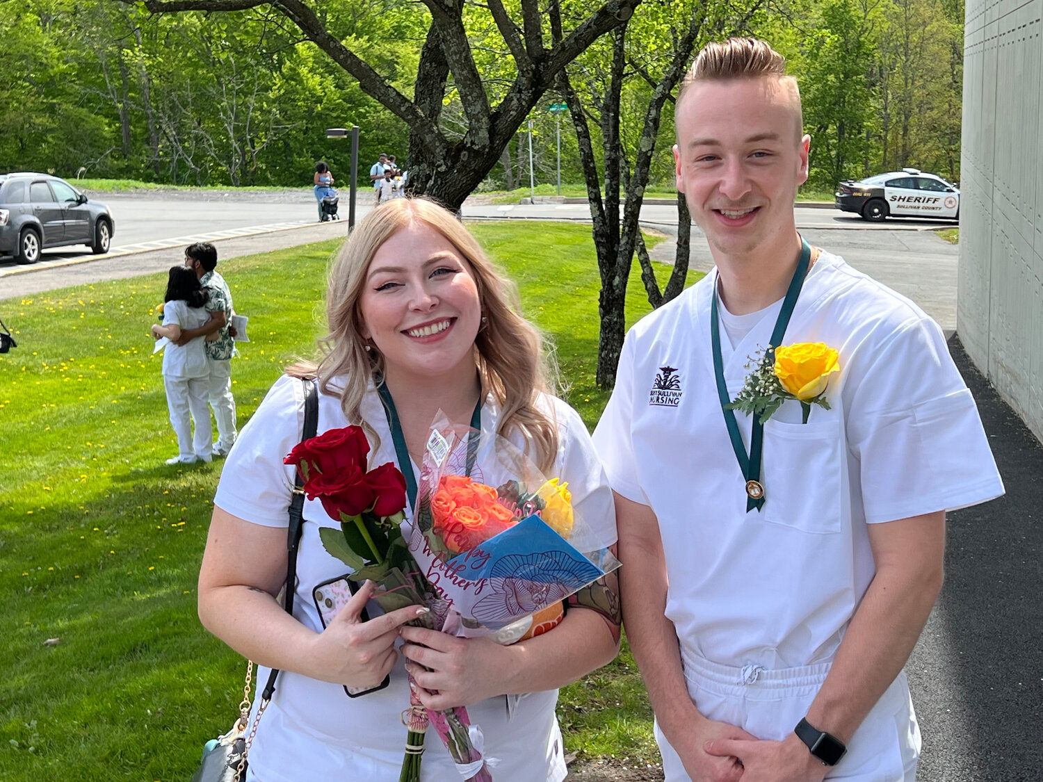 A pair of students with flowers.