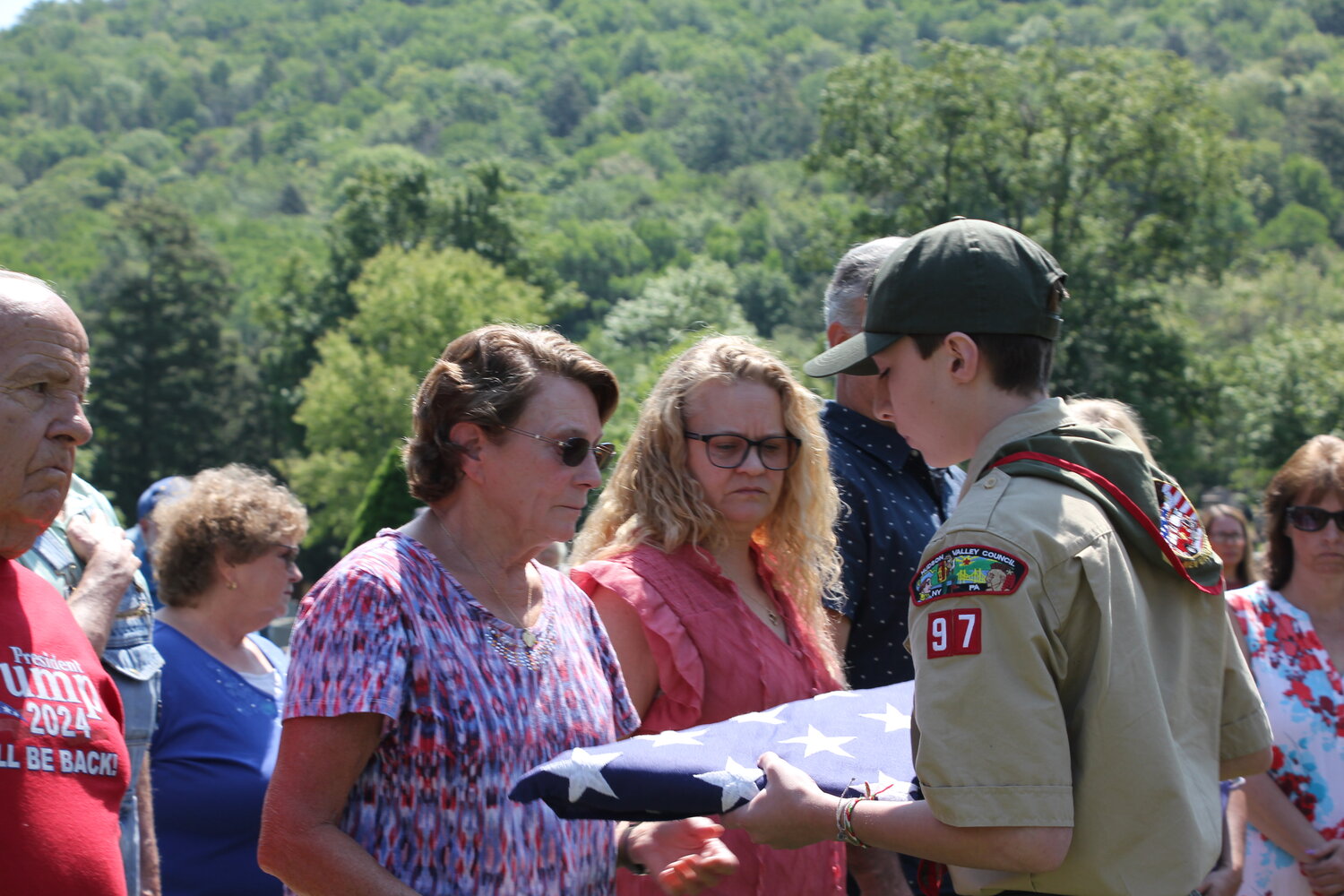 A member of Boy Scout Troop 97 accepts the flag honoring U.S. Army Veteran Herb Akerley from his wife Kathleen.