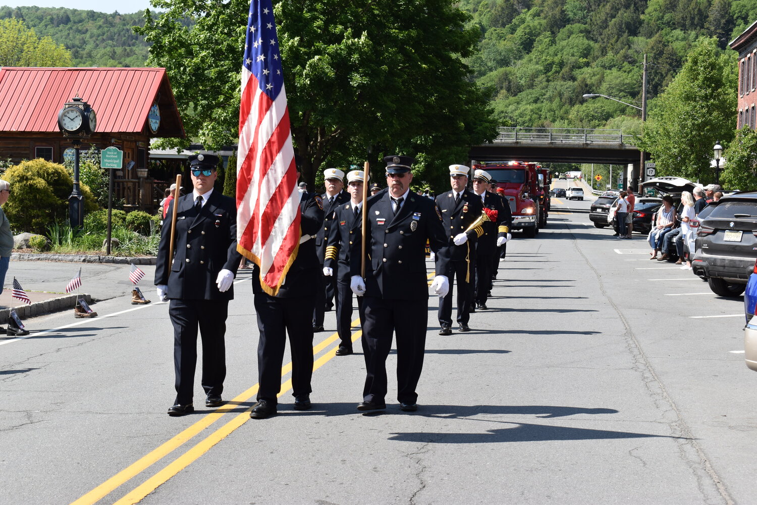 Members of the Roscoe-Rockland Fire Department march down Stewart Avenue. The Memorial Day committee set boots with flags and photos of deceased veterans along the parade route.