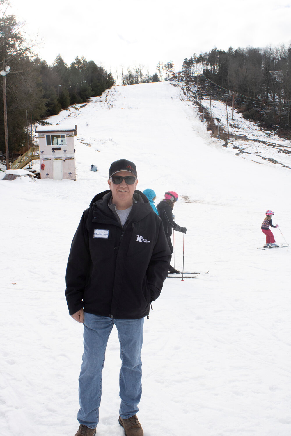 New owner Mike Taylor stands in front of the slopes of the reopened Holiday Mtn. Behind him to the left is their new race timing shed.