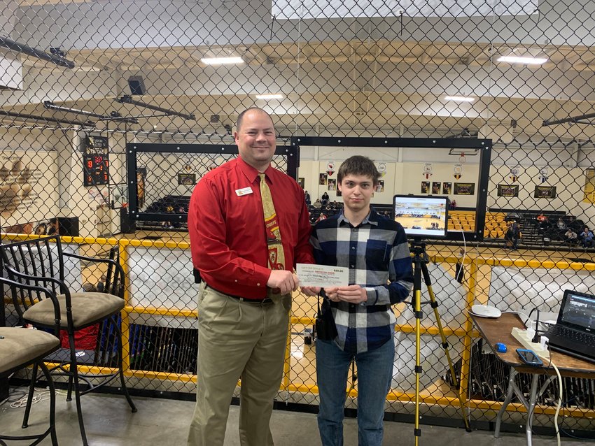 Principal Jonathan Petersen presents Smithton High School junior Jarett Davis with a $20 gift card to the Smithton Diner at a recent Smithton basketball game. Behind them is Davis&rsquo; equipment for recording and live-streaming sports games.