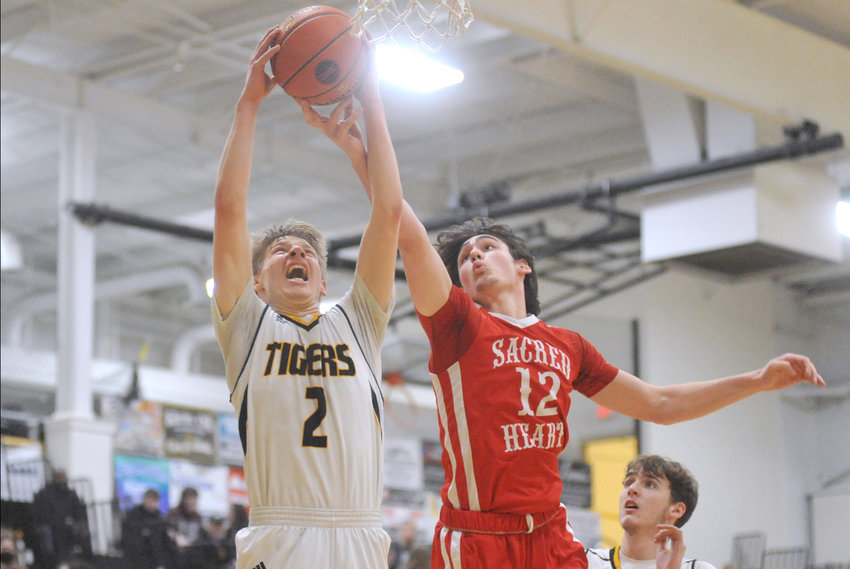Smithton junior Tom Tripp (2) and Sacred Heart junior Coen Brown (12) reach for a rebound Thursday during a 62-54 final at the Class 2 District 8 Tournament in Smithton.