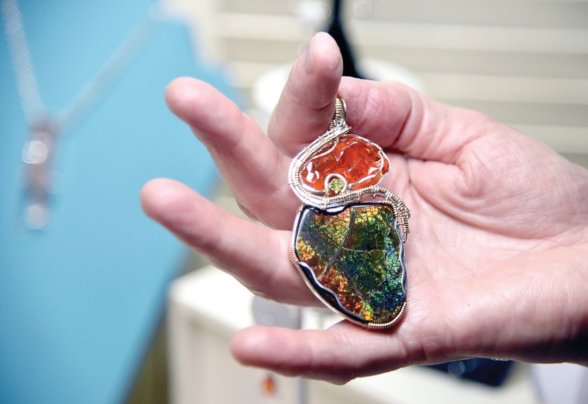 Sedalia jewelry artist Patti Zieche-Davisson holds a large wire-wrapped pendant created with a Peridot, an orange Mexican Fire Opal and an Opalized Ammonite. Zieche-Davisson, who makes her living selling work at jewelry shows across the U.S., had to reorganize last year due to the pandemic.