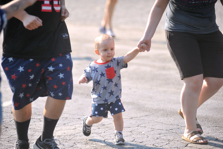 Asher Curry, 19 months, is helped by Rock and Merissa Curry on Sunday during the Pee Wee Dash at the Firecracker Mile at Liberty Park in Sedalia.