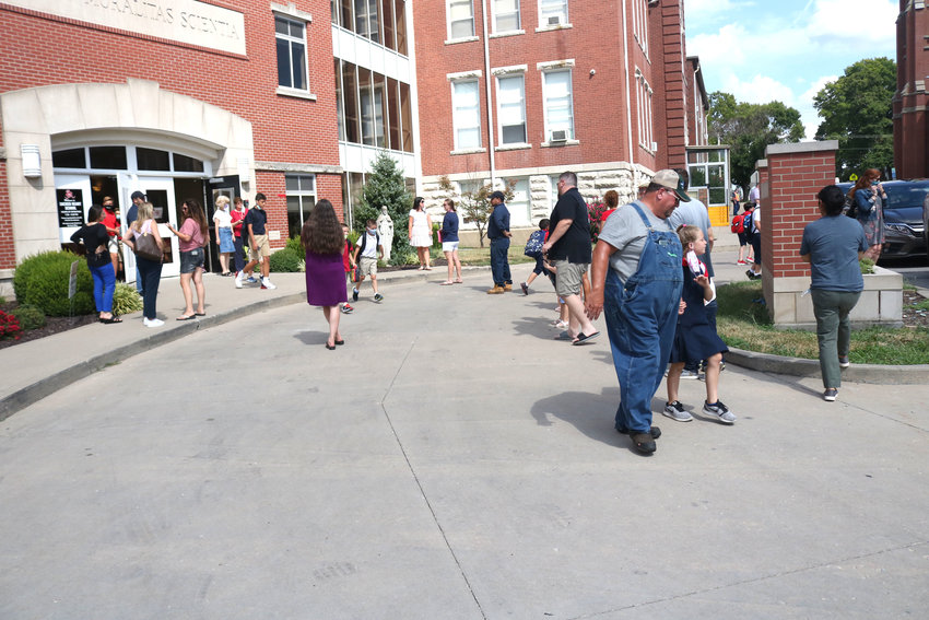 In the hot summer heat, parents and loved ones wait to receive their children as the school day ends at Sacred Heart School on Wednesday afternoon, the first day of school.