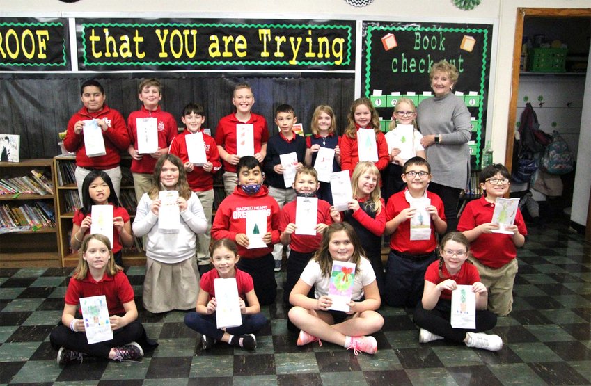 Robin Williams and her third-grade class stand together for a group photo holding the blessing bags they decorated at Sacred Heart School Wednesday morning.
