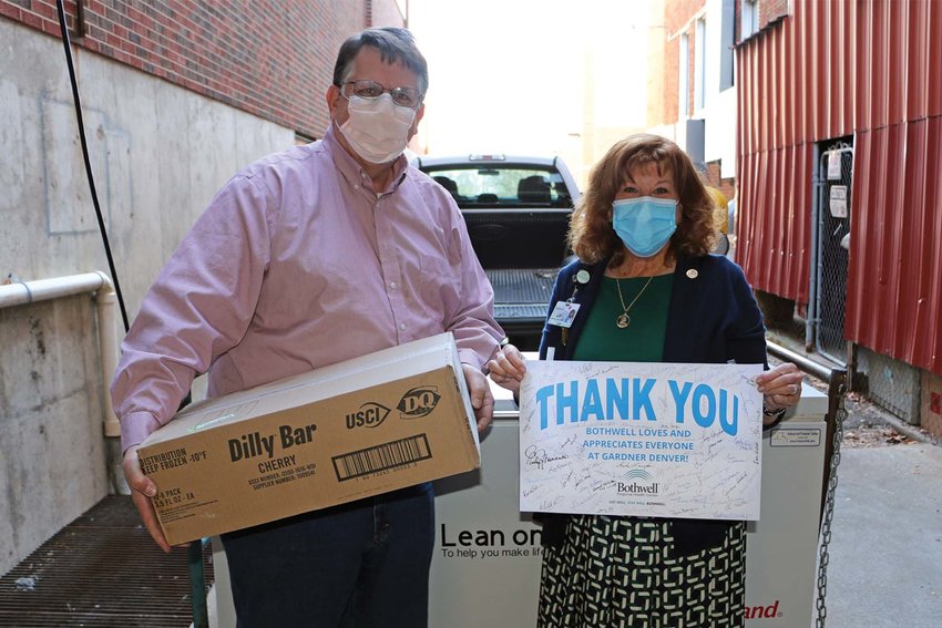 From left, David Wolf, senior safety and quality leader for Industrial Technologies &amp; Services (ITS) Americas at Ingersoll Rand, Gardner Denver's parent company, holds a box of Dairy Queen Dilly Bars, and Lori Wightman, Bothwell CEO, holds a thank you note signed by Bothwell employees. The frozen treats were inside a subzero freezer that Bothwell returned to Gardner Denver after using it to store Covid-19 vaccines for nearly a year.