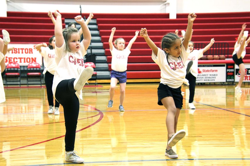 Little Gremlins Reid Nehring and Sariah Clemons do some kicks during Thursday afternoon&rsquo;s cheer clinic practice in Sacred Heart School&rsquo;s main gym. There were six cheerleaders and 40 Little Gremlins to participate in the clinic, all led by Cheer Coach Kara Hill. They performed the routine at halftime during the SHS girls basketball game Thursday night.
