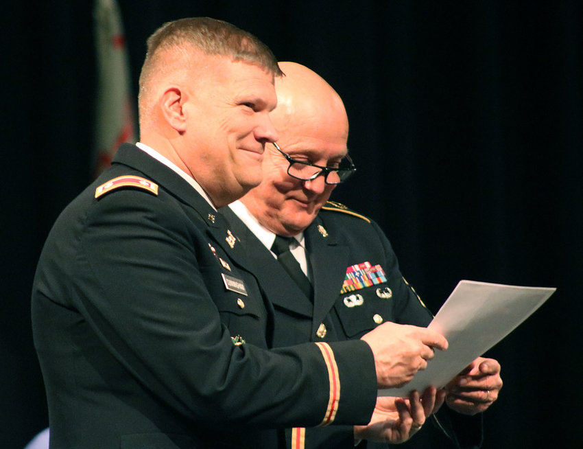 Lt. Col Cunningham and Sgt. Maj. Randall Woods stand together during the JROTC awards ceremony on April 6 hosted in the Heckart Performing Arts Center. Cunningham is showing Woods a photo of the retirement gift that the JROTC booster club purchased for Woods.