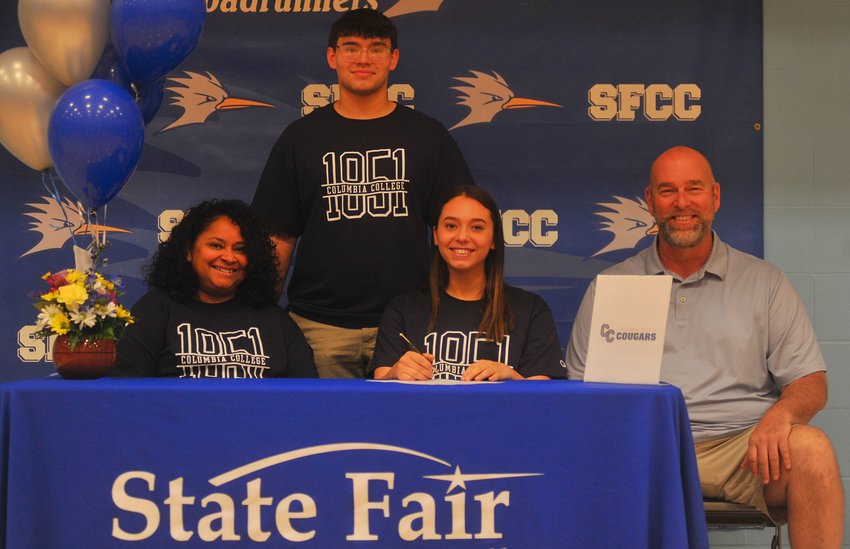Backed by her brother, Grant, State Fair Community College guard Grace Goodwin (front, middle), also surrounded by her parents Sheila and Steve, signs with Columbia College in a ceremony made official at the college on Friday, April 29.
