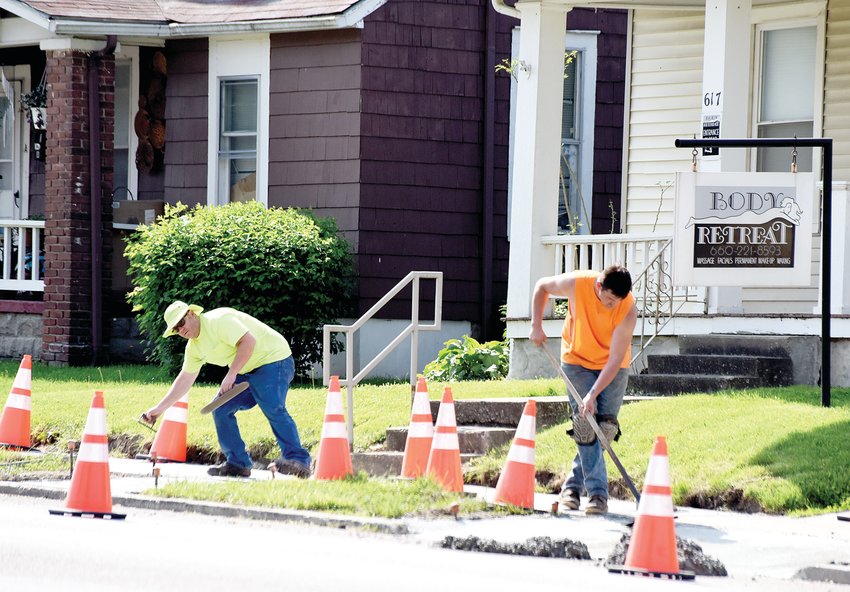 Workers take advantage of the unseasonably hot weather Tuesday morning to lay a sidewalk in the 600 block of West 16th Street. According to the National Weather Service, temperatures will reach the 90s for several days this week, which is unusual for May.
