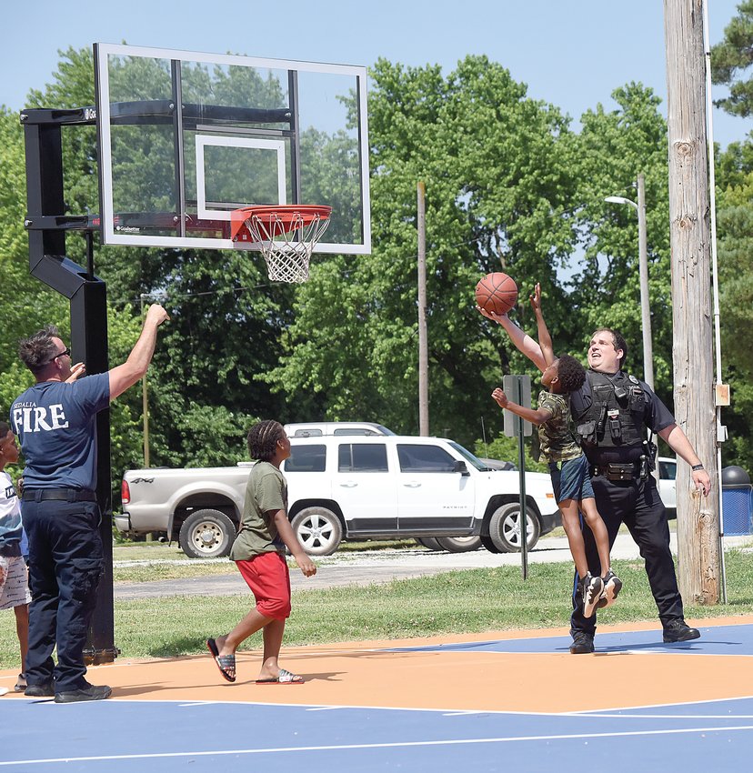 Sedalia Police Officer Derrick DeSalme and Sedalia Fire Department Firefighter and EMT Joseph Parnell play basketball with some children Saturday, during the Juneteenth celebrations at Hubbard Park. The event was Sedalia&rsquo;s 22nd Juneteenth observance.