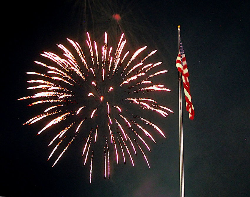 Fireworks flicker above Old Glory on July 4, 2021, at the Sedalia Parks and Recreation fireworks display on the Missouri State Fairgrounds.