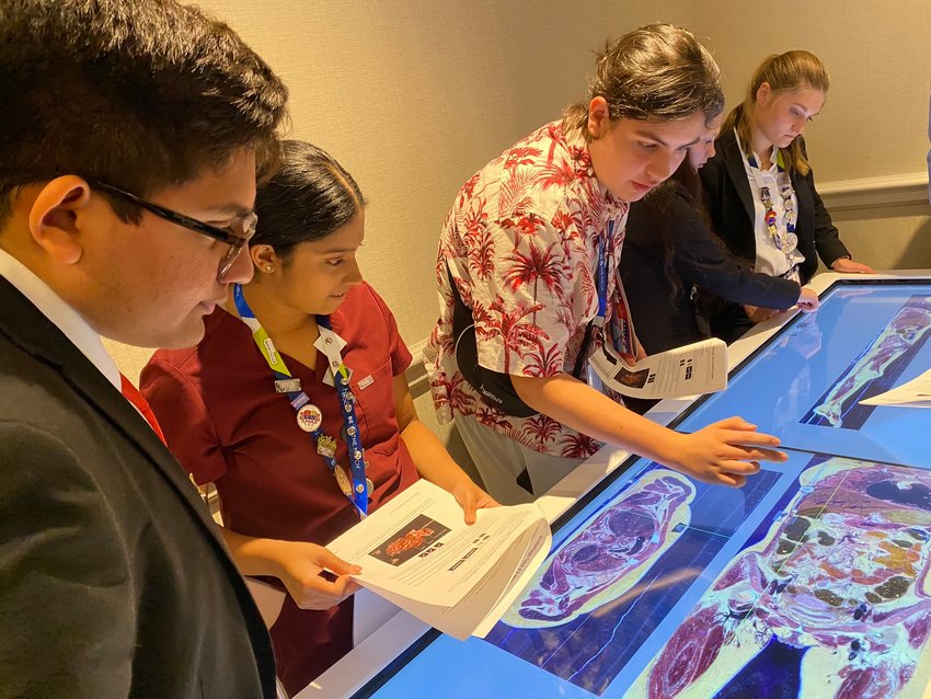 Jeffthan Glaster and other members of HOSA attend one of the educational symposiums. These were educational workshops on a variety of topics from how to get into medical school to how to do sutures. In this particular one, students used an Anatomage virtual dissection table created using high-quality images of real human cadavers. Each table has a screen that allows students to interact with the 3D cadaver to visualize anatomy exactly as it would be on a fresh cadaver. Students can interact with each body system and perform virtual dissections. In this particular photo, students were examining the effects of gastric cancer on the stomach.