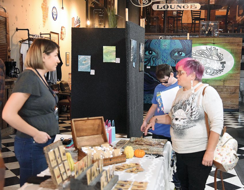 Samantha Fox and her son Logan Fox, 12, both of Sedalia, look over jewelry created by Sedalia artist Erica Lowe on Saturday. They were taking in the NoBro Art Walk at Two-Bit Barber Co. Also exhibiting at Two-Bit was Amy Hunn, with photography, and Lorie Parham, with acrylic-pour paintings.