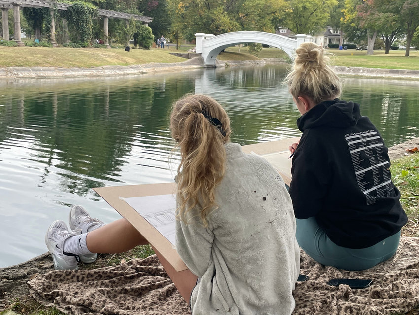 Rylee Donaldson and Cayden Box, both ninth-graders from Green Ridge, draw the newly refurbished bridge at Liberty Park pond Wednesday during the Kaysinger Senior High Schools Art Competition.