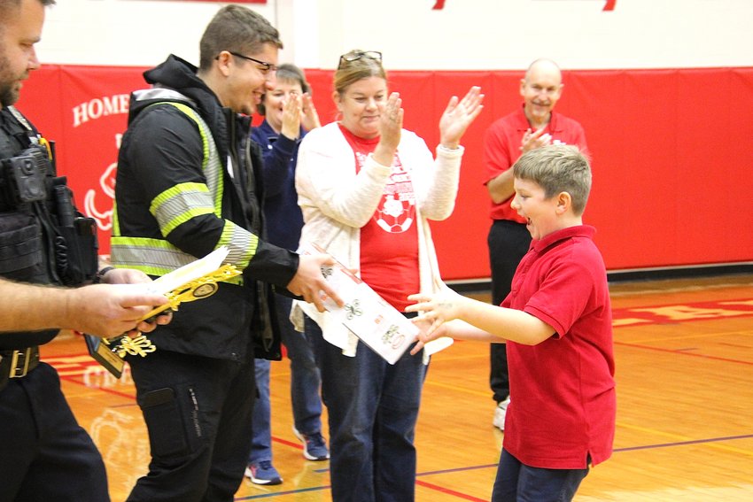 Excited Sacred Heart third grade student Auggie Kramer runs to David Chernish from In-Motion Towing, the sponsor of that drone, to accept his drone and trophy on Monday. Kramer was one of three Sacred Heart students to win a drone.