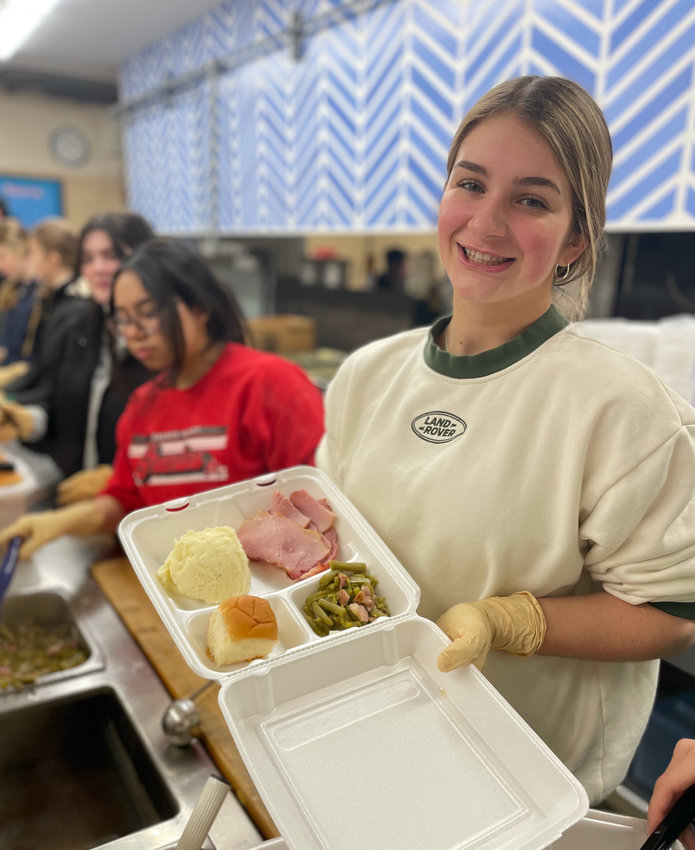 Sacred Heart sophomore Sophia Carney takes a quick break for a photo as she and students of the Sacred Heart School National Honor Society prepare over 600 meals on Saturday, Christmas Eve.