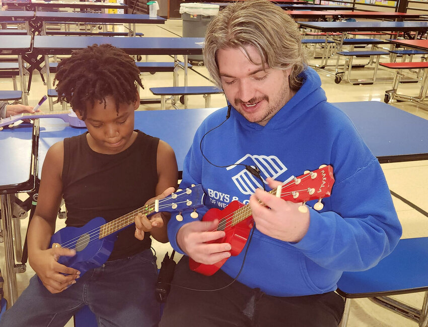Youth Development Professional Corey, right, teaches a Boys &amp;amp; Girls Clubs of West Central Missouri member how to play the ukulele.