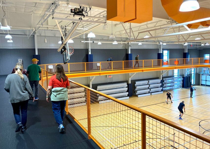 Several people take an afternoon stroll around the walking track as a pickleball game is played on the courts below Friday, March 17 at the Heckart Community Center. March 18 marks the one-year anniversary of the community center.