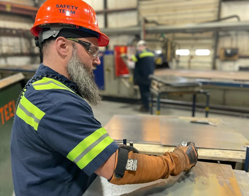 Supervisor Lucas Miller marks steel plates at Alro Steel for shipping as Randy Templemire operates a large plasma cutter in the background Monday.   Photo by Chris Howell | Democrat