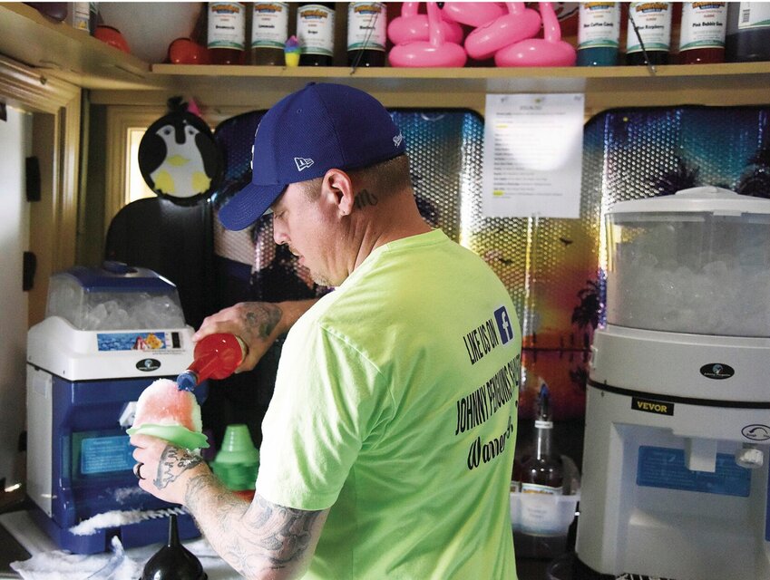 On Wednesday, April 19, Johnny Tevis pours a combination of pink bubblegum and blue cotton candy flavorings over shaved ice at Johnny Penguins in Warrensburg. Tevis co-owns the business with his wife, Jamie. This is the second year for the shop.   Photo by Faith Bemiss | Democrat