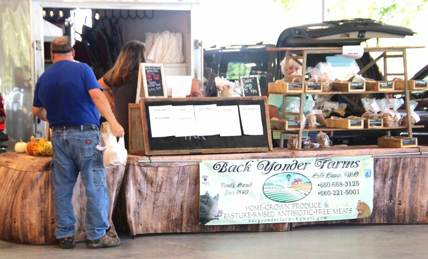 A customer looks over the selection at the Back Yonder Farms stand at the Sedalia Area Farmers&rsquo; Market in October 2021. The market's 15th season begins Friday, May 5.   File photo by Skye Melcher | Democrat