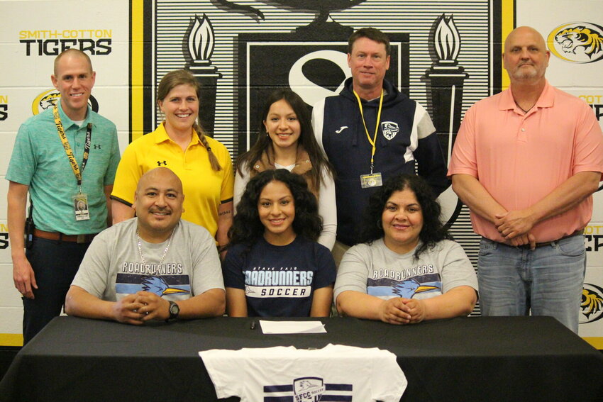 Smith-Cotton senior Emily Ramirez celebrates accepting a scholarship to play soccer for State Fair Community College with Wednesday's signing ceremony at the high school. She is pictured seated next to her parents, Edgar and Claudia, as well as behind her (left to right) S-C Assistant Principal Joseph Doyle, Lady Tigers head coach Meredith Brick, sister Adamaris, SFCC head coach Michael Poropat, and S-C Athletic Director Rob Davis.   PhotoCredit: Photo by Bryan Everson | Democrat