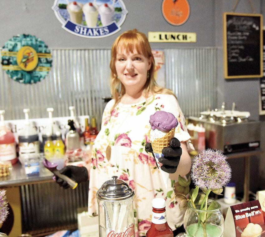 On Thursday, May 4, Lynn Paszkiewicz hands out a double-dipped cone of Birthday Cake and purple Ube ice cream. Lynn Paszkiewicz co-owns Cow Bird Creamery and Sweets with her husband, Christopher Paszkiewicz. The couple recently moved their eatery to a downtown location.   Photo by Faith Bemiss | Democrat