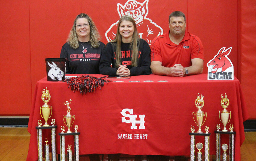 Sacred Heart's Emma Siron, center, poses for a picture with her parents, Marlo and Sean, in a signing ceremony at the school on April 25.   PhotoCredit: Photo by Bryan Everson | Democrat