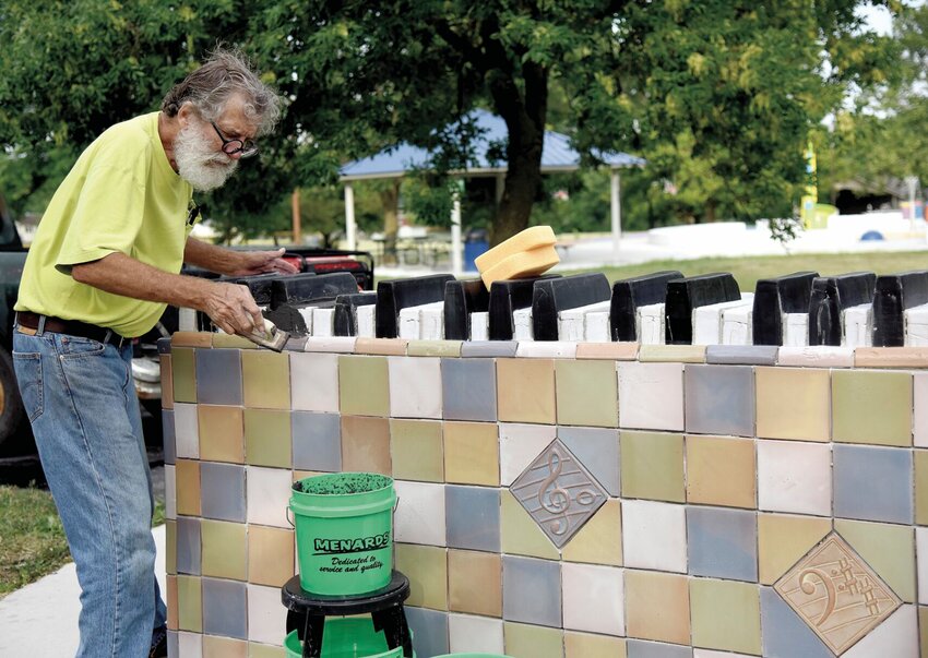 Wednesday morning, June 28 at Hubbard Park, Sedalia artist Alan Weaver places grout on a music-themed sculpture he created with handcrafted tiles. The 2,000-pound piece, &quot;The Structure of Music,&quot; a piano, is one of three pieces Weaver will install commemorating the park's 100th anniversary.      Photo by Faith Bemiss | Democrat